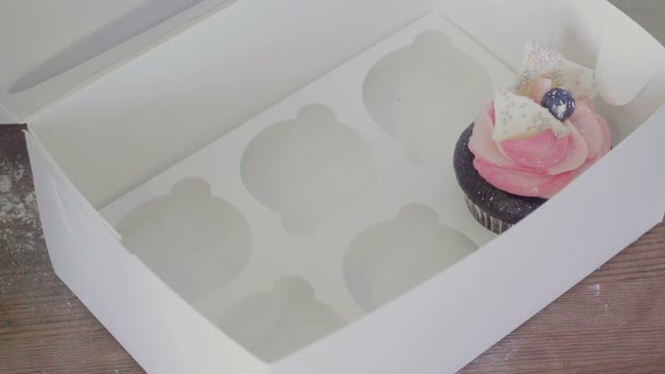 Vista superior de una chica pone cupcakes en una hermosa caja de regalo — Vídeos de Stock
