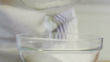 Mutfakta bir kız cam bir kaseye un döküyor.