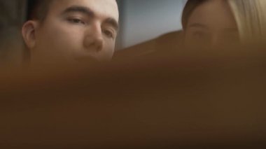 Çekici bir çift akıllı telefon kullanarak masada oturuyor, internette geziniyor, online alışverişleri tartışıyor, romantik bir akşam yemeği için restorandan yemek sipariş ediyor.