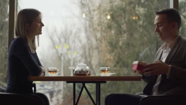 Mężczyzna i kobieta siedzą naprzeciwko siebie w kawiarni lub restauracji przy oknie i komunikują się. Randka w kawiarni lub restauracji. Romantyczna atmosfera — Wideo stockowe