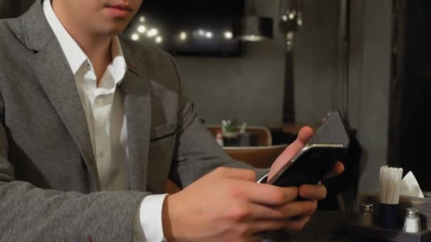 A man is sitting at a table in a cafe, browsing web pages on the Internet, a woman comes up from behind and covers his eyes with her hands and sits down at his table — Stock Video