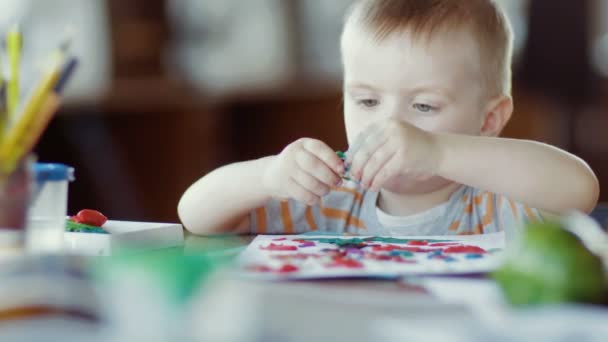 Een kind speelt met kleurrijke plasticine aan tafel — Stockvideo