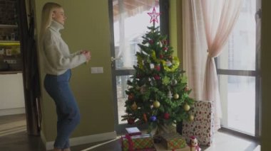 Süveter giyen güzel sarışın bir kız Noel ağacına yaklaşır ve bir Noel balosu düzenler. Evin penceresinin yanında altında hediyeler olan bir Noel ağacı..