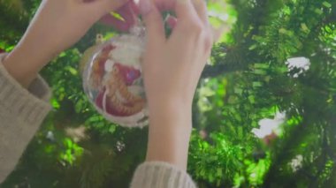 Kadınların elleri Noel ağacına bir Noel topu asar. Yakın plan. Noel zamanı. Yeni Yıl.