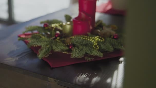 Вічнозелений вінок з двома червоними свічками і однією золотою свічкою. Різдвяні традиції та звичаї християн напередодні свята.. — стокове відео