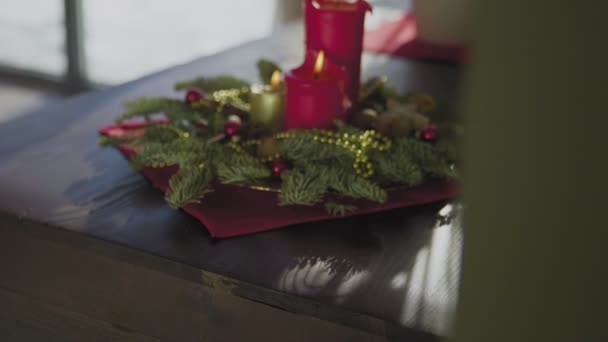 2本の赤いキャンドルと1本の黄金のキャンドルを持つ常緑の花輪。クリスマスの伝統と休日の前夜のキリスト教徒の習慣. — ストック動画