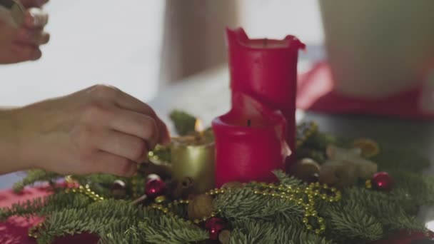 Tanınmayan bir kız, iki kırmızı mum ve bir altın mumla her daim yeşil bir çelenk yakar. Noel arifesinde Hıristiyanların gelenek ve adetleri. Bayramın sembolü.. — Stok video