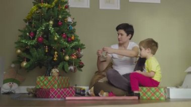 Bir anne ve çocuk güzel bir paket kağıdına hediye koyar. Noel zamanı. Şenlik havası.
