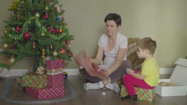 母親と子供は美しい包装紙に贈り物を詰めます。クリスマスだ。お祭り気分. — ストック動画