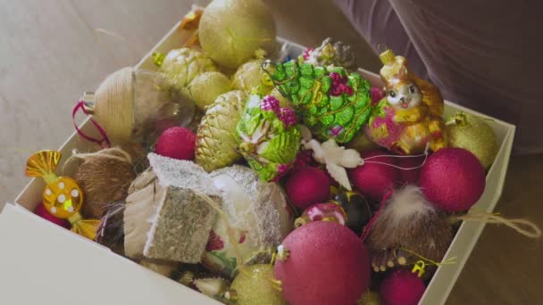 Un homme emballant des décorations de Noël dans une boîte en carton. Transfert de bibelots emballés et de guirlandes roulées pour entreposage pour l'année suivante. — Video