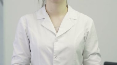 Doktorun yakın plan fotoğrafı. Tıbbi önlüklü bir kadın boynuna steteskop takıyor.