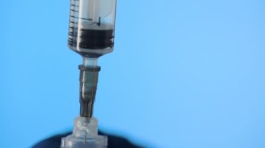Doktorun elleri mavi arka planda aşı için aşı hazırlıyor.