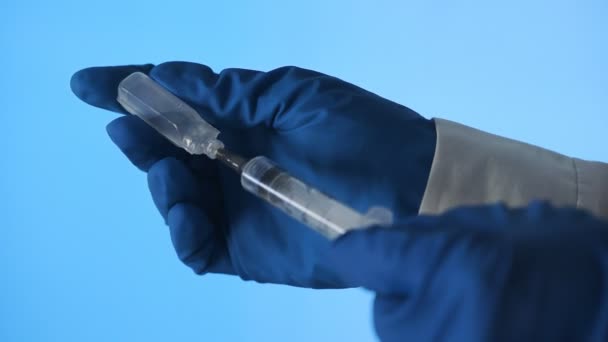 Close-up de um médico mãos preparando uma vacina para injeção em um fundo azul — Vídeo de Stock