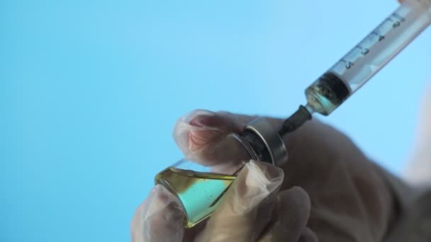 Close-up van een arts die een vaccin maakt voor injectie op een blauwe achtergrond — Stockvideo