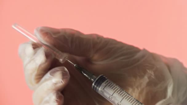 Close-up van een arts die een vaccin bereidt voor injectie op een rode achtergrond — Stockvideo