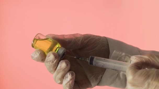 Крупный план врачей руки подготовки вакцины для инъекции на красном фоне — стоковое видео