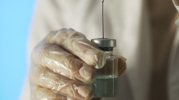 Primo piano delle mani dei medici che tengono una siringa con una soluzione limpida e versano una sostanza rossa in una fiala. Il processo di sviluppo di un vaccino, ricerca sperimentale in un laboratorio medico — Video Stock