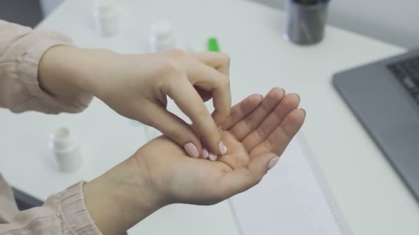 Une fille méconnaissable prend des pilules de sa main et les lave avec de l'eau, gros plan — Video