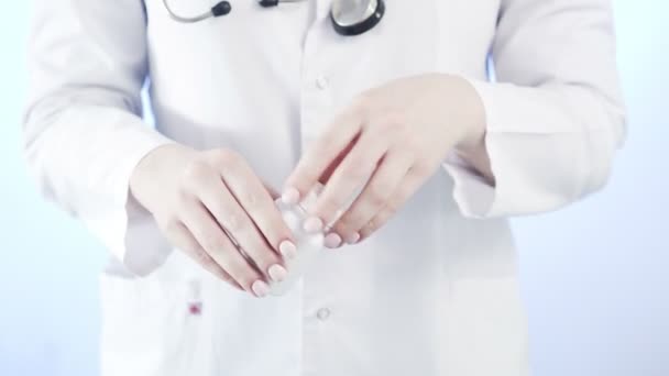 Close-up of an unrecognizable woman, a doctor, holding a jar of pills and throwing it into her hand — Stock Video