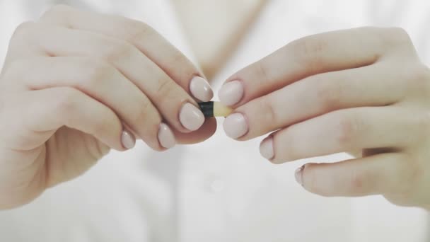 A woman opens a yellow medical capsule and spills yellow powder from it — Stock Video