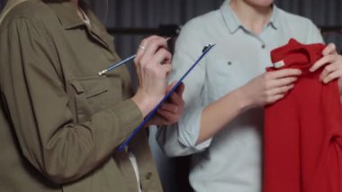 Tanınmayan bir kadın elinde bir tablet kağıt tutuyor ve notlar alıyor. Yakın plan.