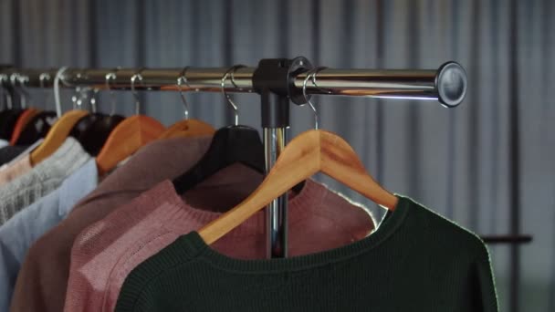 Una tienda de ropa con ropa en los hangers.Close-up. Una mano de mujer cuelga una bolsa en una percha — Vídeos de Stock