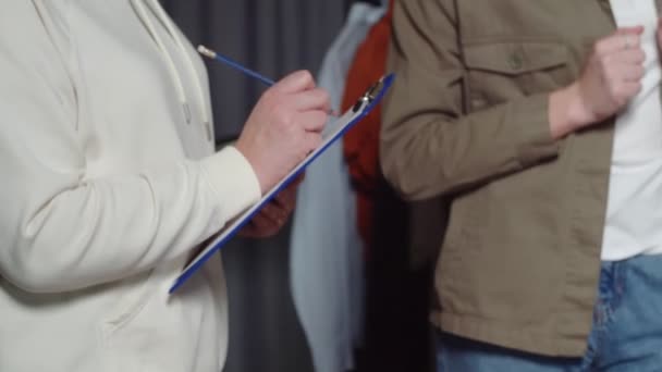 Een onherkenbare vrouw houdt een tablet vast met een vel papier en maakt aantekeningen. Close-up — Stockvideo