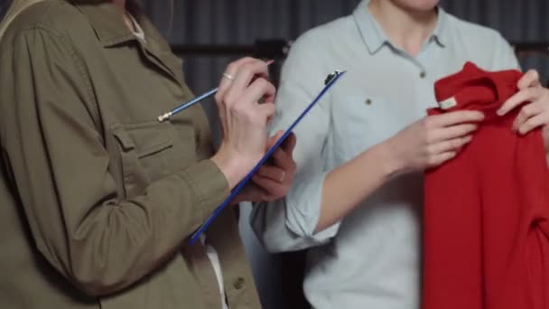 Una mujer irreconocible sostiene una tableta con una hoja de papel y toma notas. Primer plano — Vídeo de stock