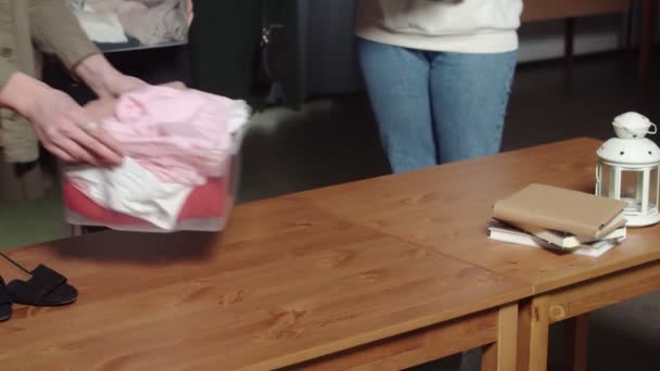 Mulheres irreconhecíveis colocam caixas de plástico com roupas na mesa. Close-up — Vídeo de Stock