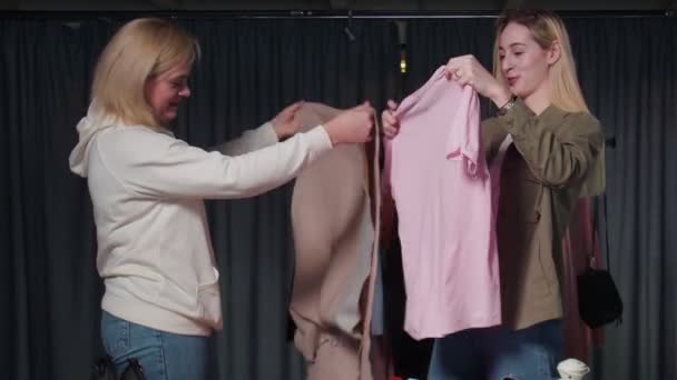 Twee vrolijke vrouwen vouwen kleren, zetten dingen op orde. — Stockvideo