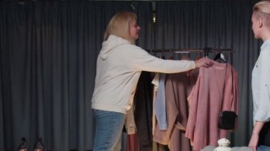 Giyim mağazasında bir kadın ve bir kız kendileri için bir şeyler seçer, kıyafetleri denerler. Alışveriş.