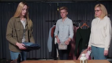 Kadınlar masanın üzerine plastik kutular koyarlar. Giysiler