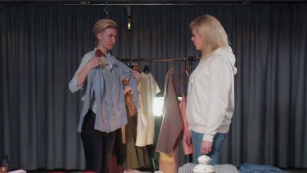 A woman and a girl in a clothing store choose things for themselves, try on clothes. Shopping — Stock Video