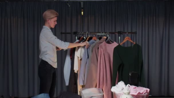 Młoda kobieta wybiera ubrania w sklepie i robi im zdjęcia przez telefon.. — Wideo stockowe
