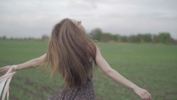 Jovem feliz em vestido escuro com estampa floral se divertindo ao ar livre no campo de geen. Menina beleza girando e rindo. maravilhoso smile.rotation meio tiro cor plana não graduado — Vídeo de Stock