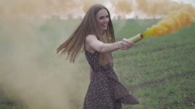 Çiçek baskılı koyu renkli mutlu genç kadın geen alanında açık havada eğleniyor. Turuncu sis bombası dönen ve gülen güzellik kız.harika gülümseme.orta çekim notsuz düz renk yavaş hareket
