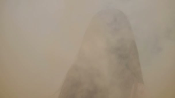 Joyeux jeune femme en robe sombre avec imprimé floral s'amusant en plein air dans la fumée colorée orange. Fille de beauté avec bombe de fumée orange filant et riant. caméra suivre de près non classé 