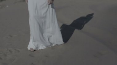 Güneş gölge yavaş düz renk damla iken beach kumulları beyaz elbiseli üzerinde yürüyen kadın ayakları