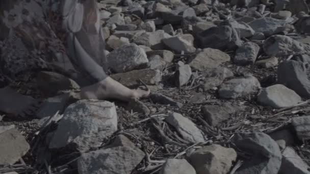 Close-up detail van een dames voet in een lange jurk staande op grote stenen met grond egale kleur — Stockvideo