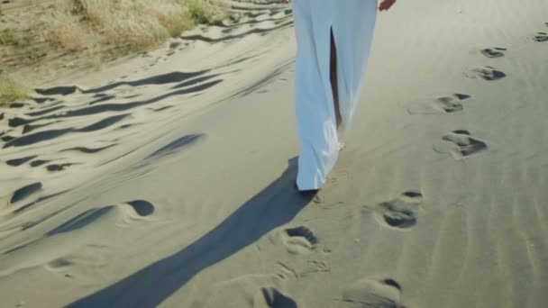 Voeten van vrouw lopen op strand duinen in witte jurk, terwijl de zon daalt schaduw — Stockvideo