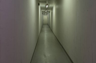 Long, tight and empty hallway on an eye-level angle with yellow-greenish light
