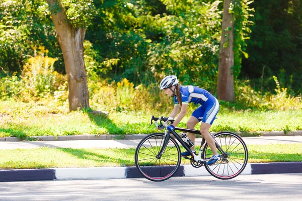 Ciclista fêmea monta uma bicicleta de corrida na estrada — Fotografia de Stock