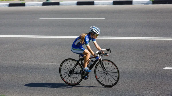 Ciclista fêmea monta uma bicicleta de corrida na estrada — Fotografia de Stock