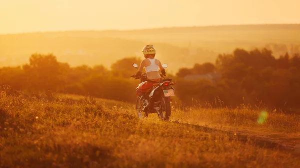 Radfahrerin bei Sonnenuntergang, Motorradfahrerin. — Stockfoto