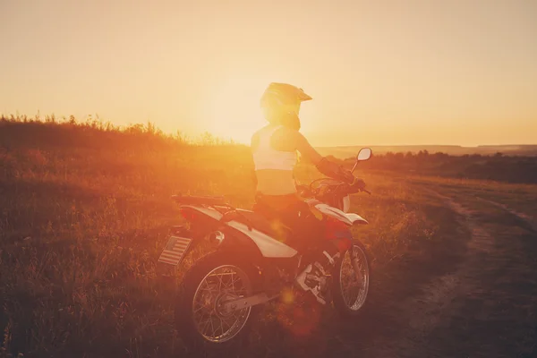 Γυναίκα ποδηλάτης στο ηλιοβασίλεμα, θηλυκό μοτοσικλέτα. — Φωτογραφία Αρχείου