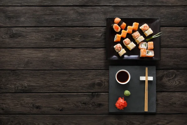 Sushi maki a rohlíky na černé rustikální dřevo. — Stock fotografie