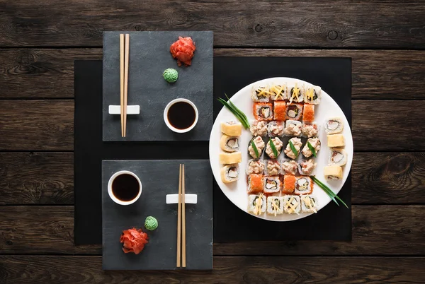 Set Sushi Maki und Rollen aus rustikalem schwarzem Holz. — Stockfoto