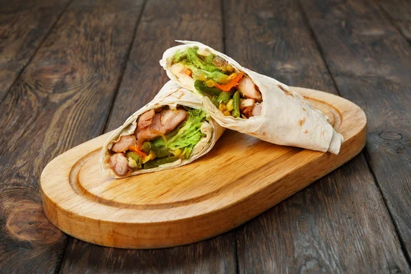 Burrito med kyckling och grönsaker på trä skrivbord — Stockfoto