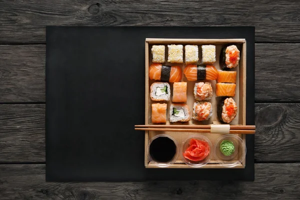 Set di sushi maki e rotoli in legno nero rustico . — Foto Stock
