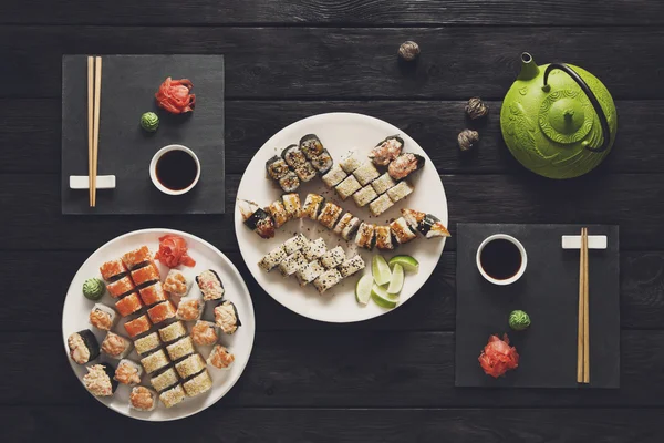 Set of sushi maki and rolls at black rustic wood. — Stock Photo, Image